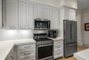 Kitchen featuring white shaker-style cabinetry, stainless steel appliances, a white subway tile backsplash, and light-colored countertops