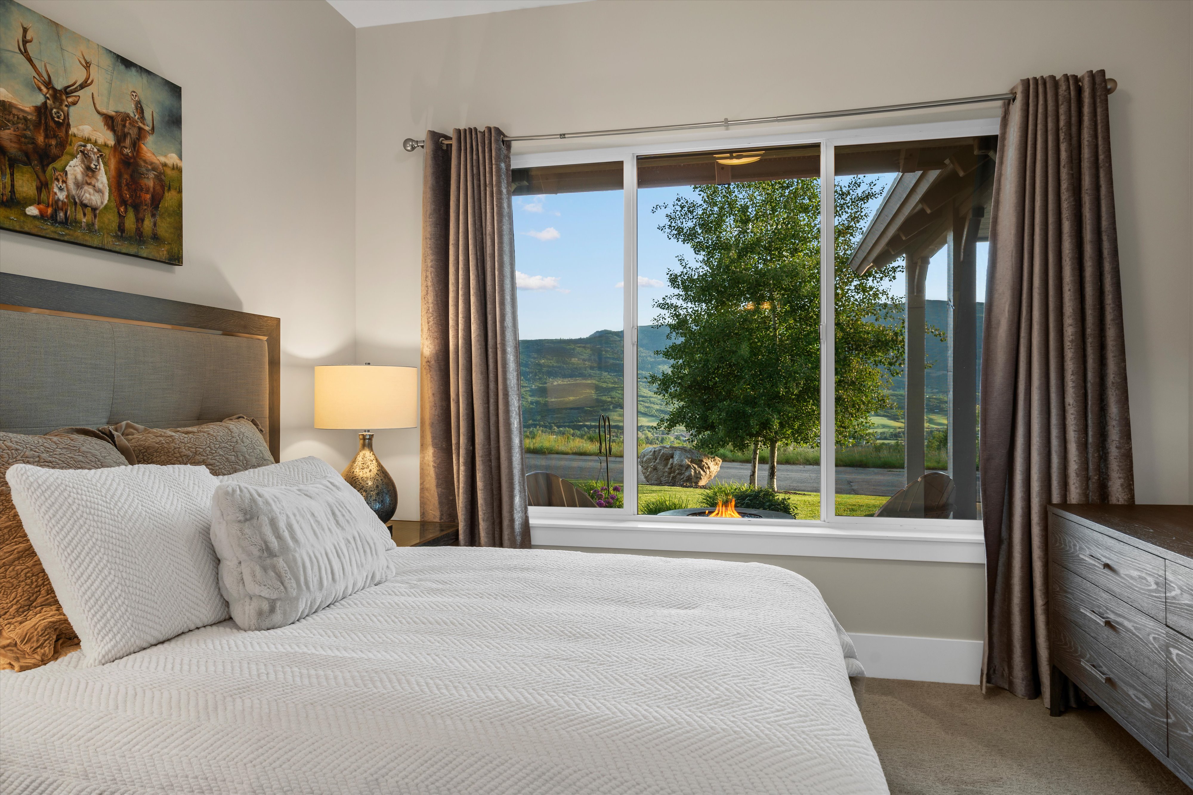 Expansive window featuring a mountain backdrop and outdoor fire pit