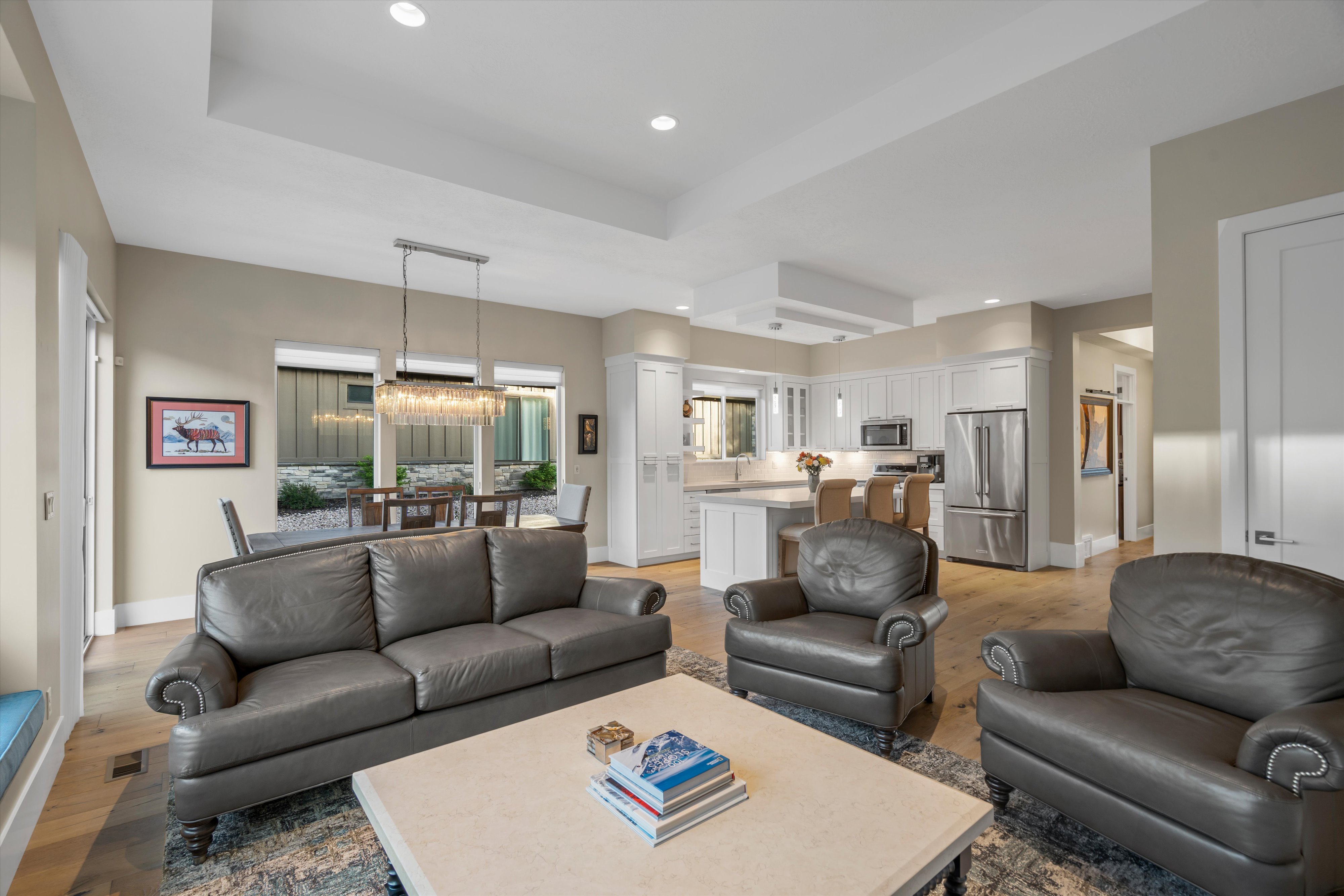 Open-concept living area featuring wood-finish flooring, recessed lighting, and a tray ceiling