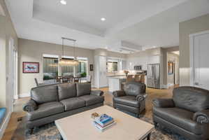 Open-concept living area featuring wood-finish flooring, recessed lighting, and a tray ceiling