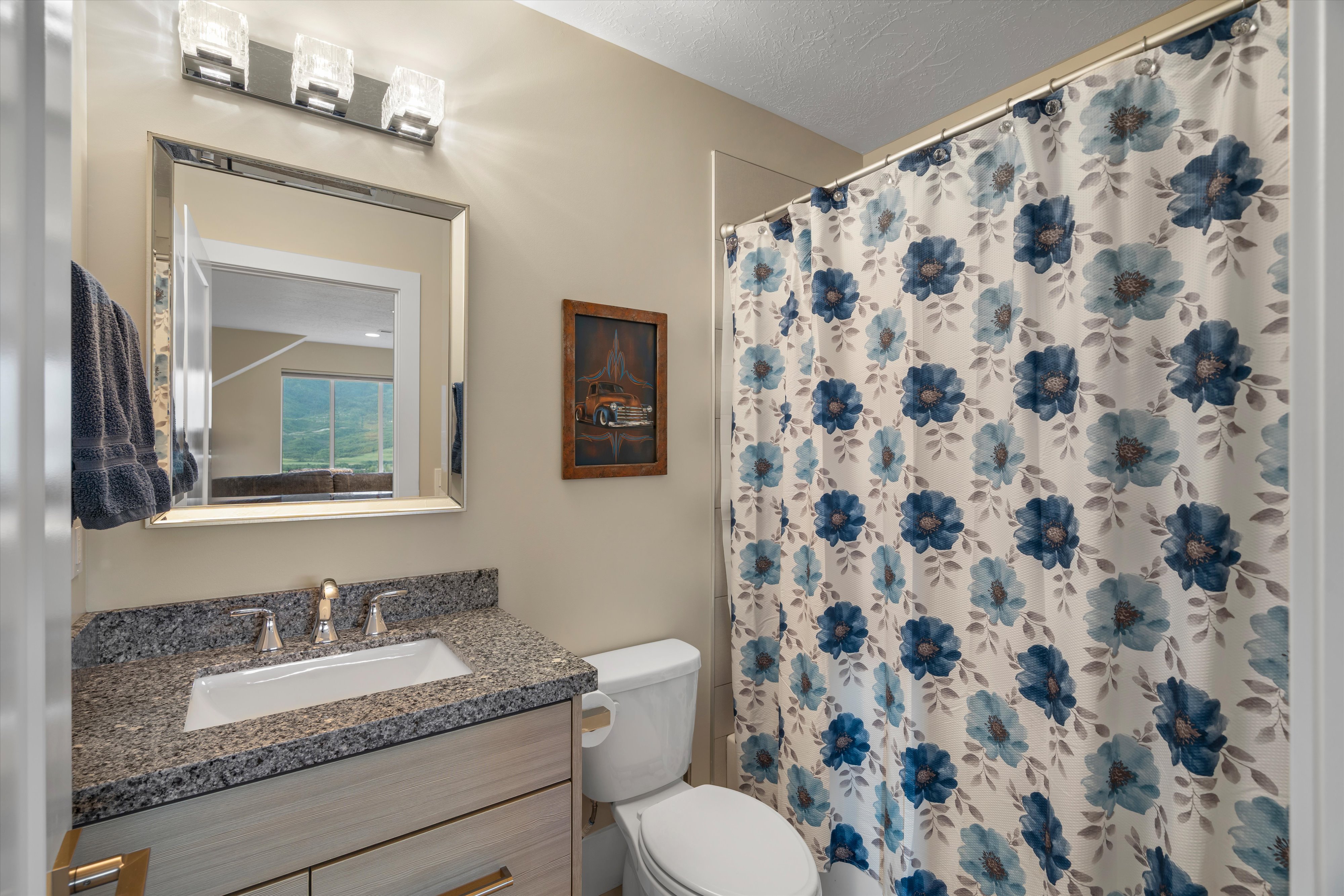 Bathroom featuring a vanity with a light wood-finish cabinet, speckled countertop, and rectangular undermount sink