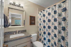 Bathroom featuring a vanity with a light wood-finish cabinet, speckled countertop, and rectangular undermount sink