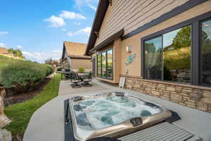 Exterior patio featuring an integrated hot tub, concrete surfacing, and a dining area