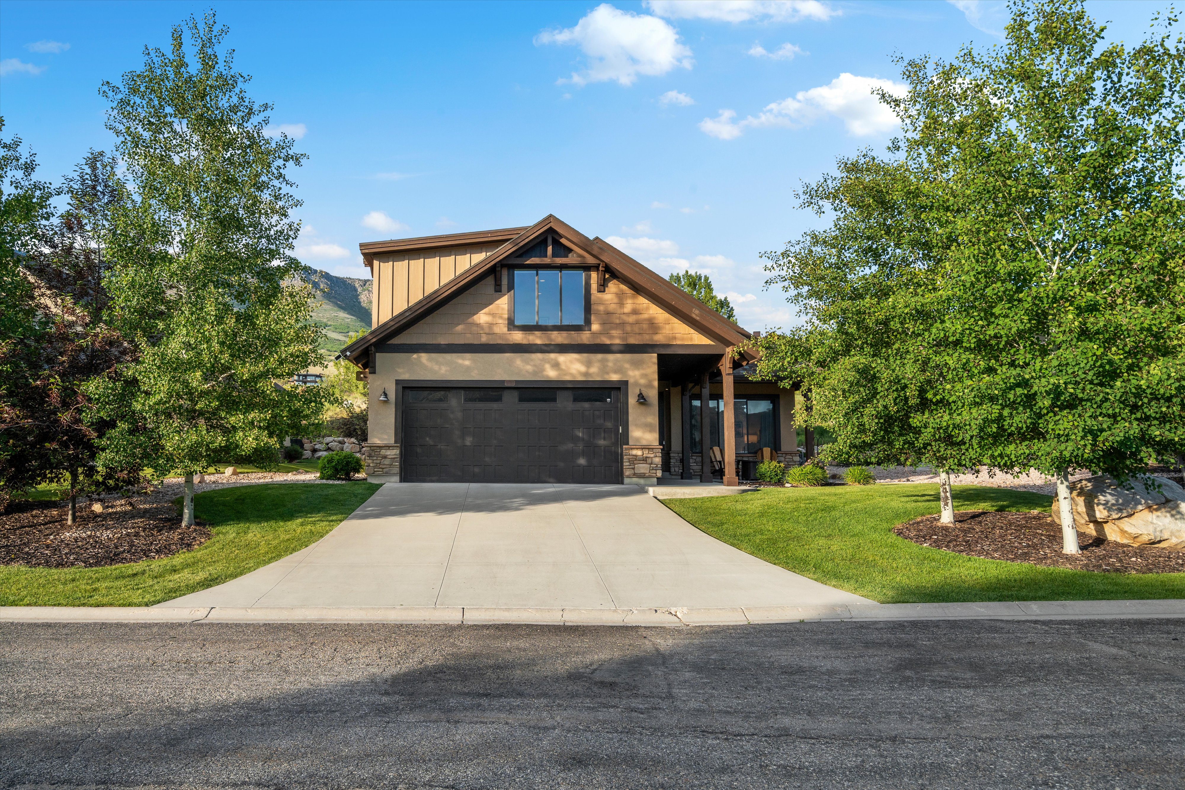 Front facade featuring a two-car garage, covered porch entry, and a prominent gable with board and batten siding