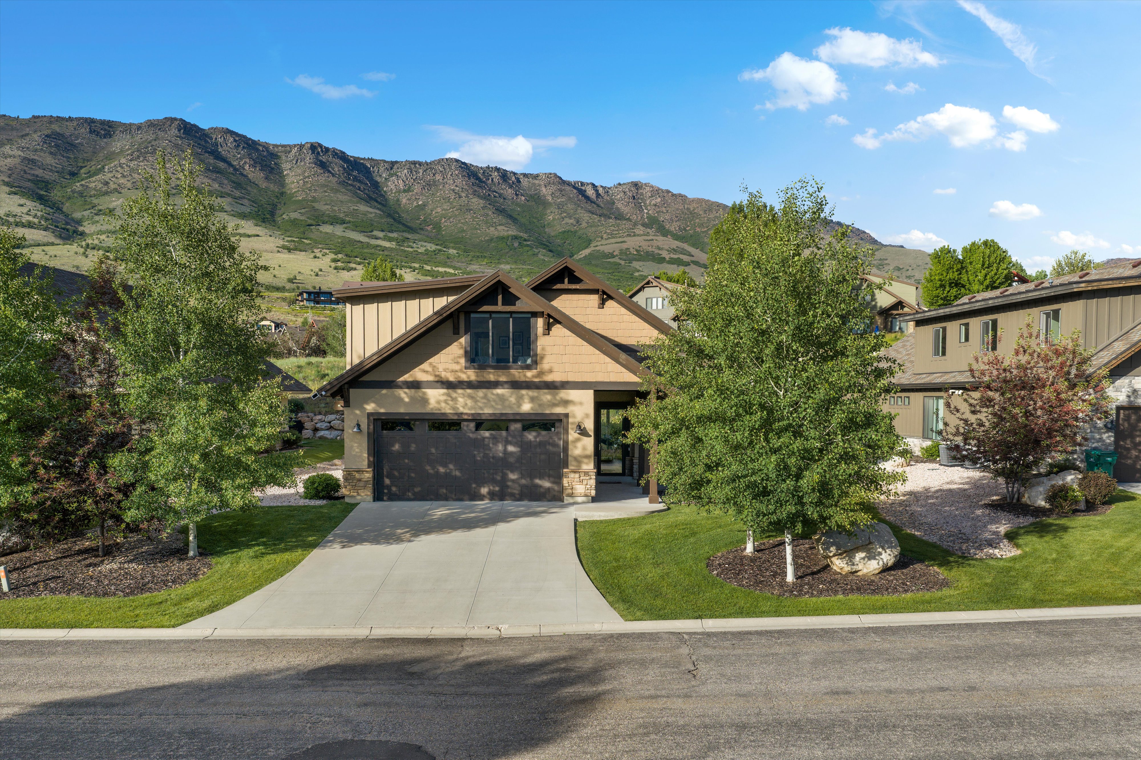 Contemporary property featuring a neutral-toned facade with stone accents and a prominent two-car garage