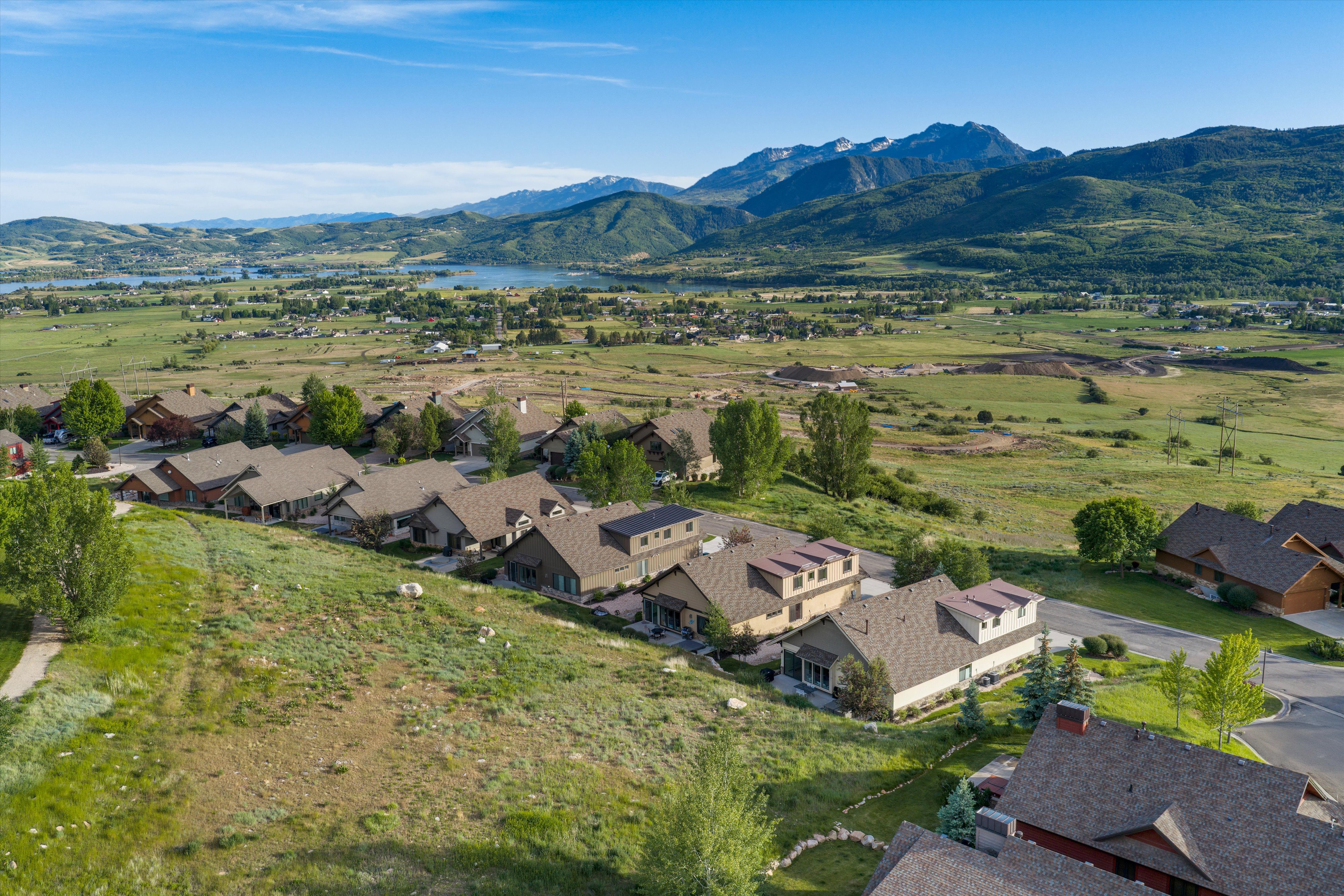 Aerial perspective showcasing a residential community with contemporary architecture, multiple homes featuring dormer windows, and a paved road