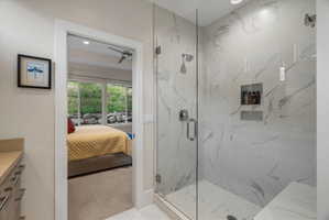Glass-enclosed shower featuring large format marbled tile, a built-in bench, and dual recessed niches