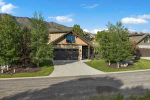Craftsman-style home featuring a two-car garage, concrete driveway, and natural wood and stone facade