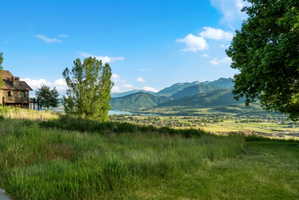 Expansive green hillside property featuring distant mountain ranges and a body of water