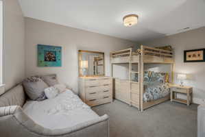 Carpeted bedroom featuring a light-toned bunk bed, a matching dresser with a mirror, and a daybed