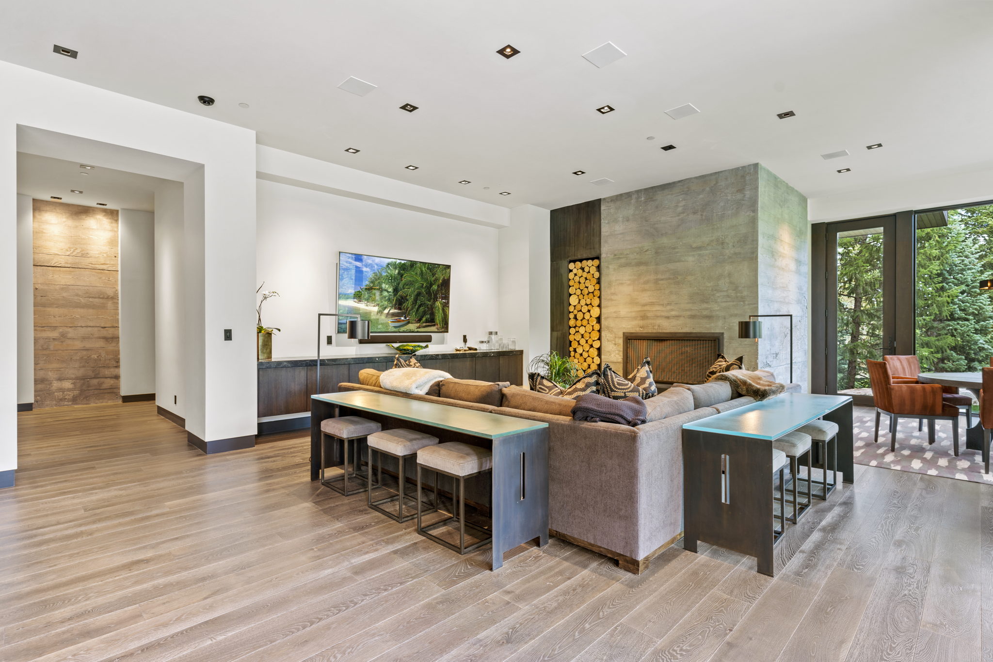 Spacious living area featuring light wood-finish flooring, a contemporary fireplace with a concrete surround, and a built-in wood storage niche