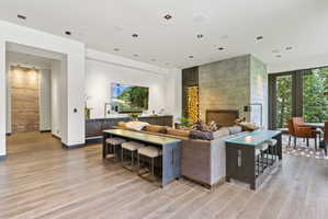 Spacious living area featuring light wood-finish flooring, a contemporary fireplace with a concrete surround, and a built-in wood storage niche