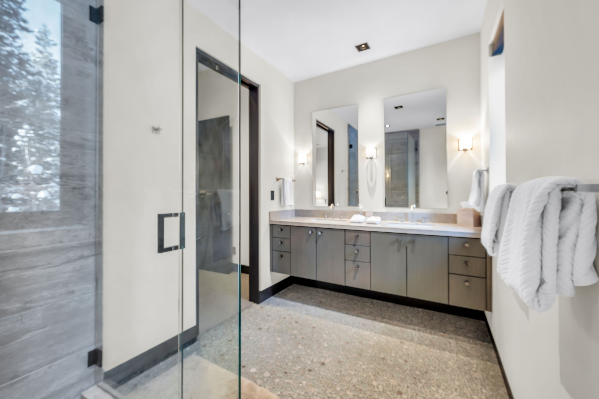 Bathroom featuring a dual vanity with light countertops, recessed sinks, and sconce lighting
