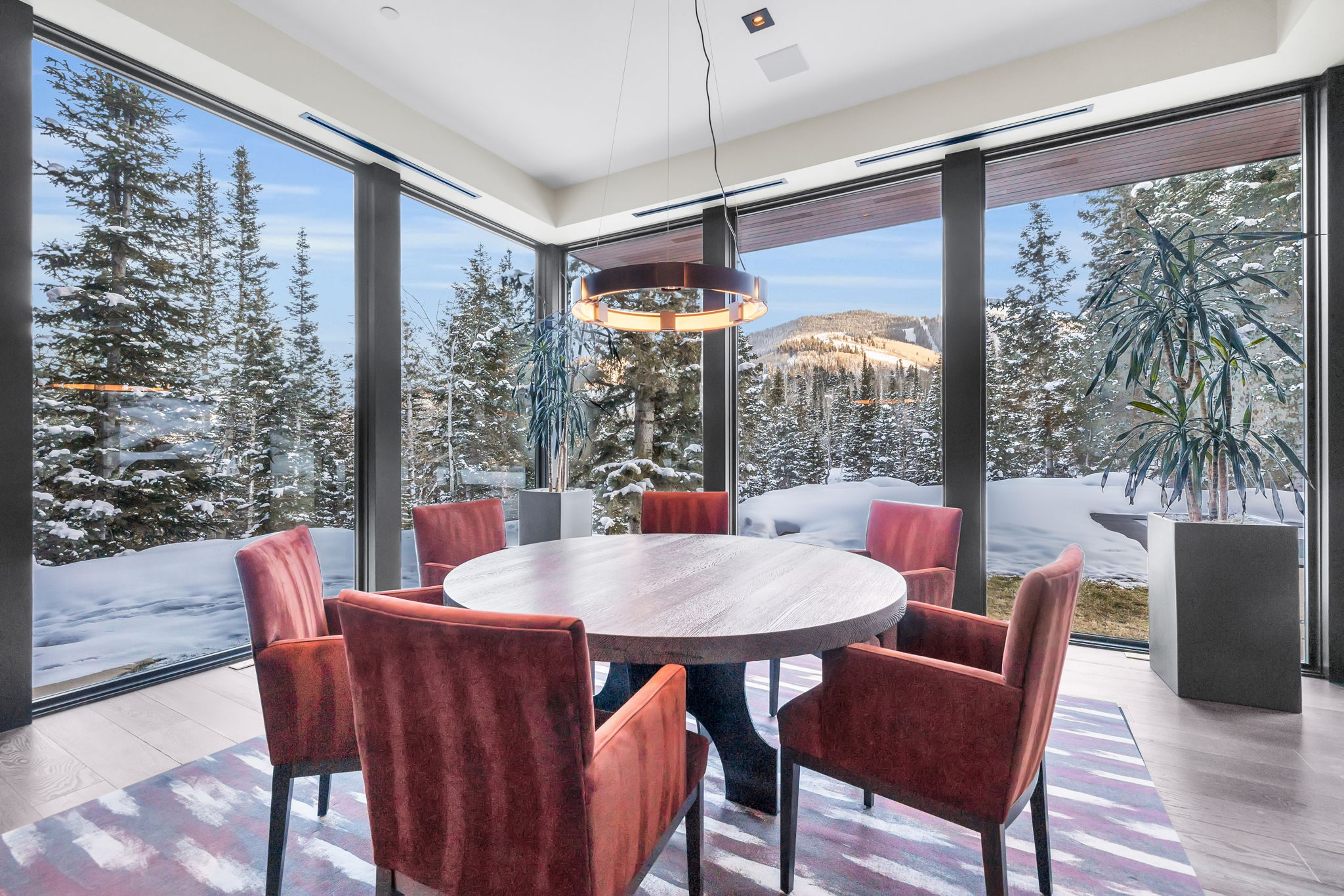 Dining area featuring expansive floor-to-ceiling windows, offering panoramic mountain scenery