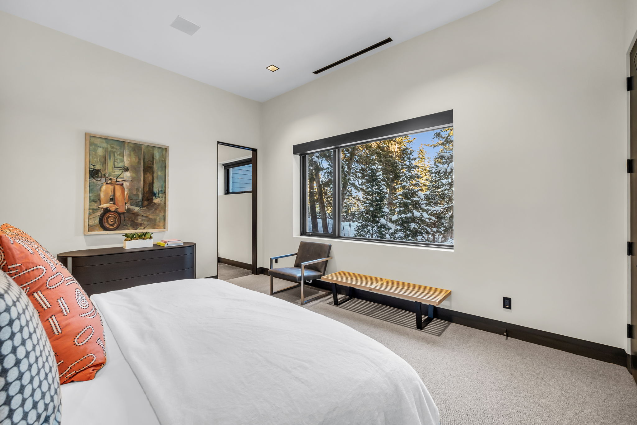 Spacious room featuring a large window with exterior winter scenery, light-toned carpeting, dark baseboards, and recessed lighting