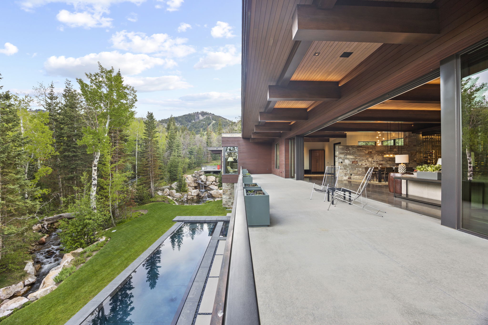 Expansive outdoor patio with an infinity-edge pool, providing direct access to the interior living space through large sliding glass doors