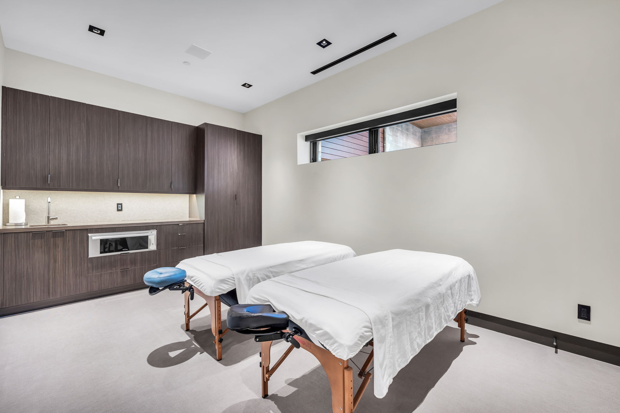 Spacious room featuring dark wood-finish cabinetry, a built-in stainless steel microwave, and a wet bar with an undermount sink