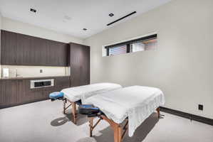 Spacious room featuring dark wood-finish cabinetry, a built-in stainless steel microwave, and a wet bar with an undermount sink