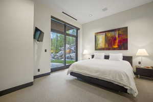 Room featuring floor-to-ceiling glass doors, recessed ceiling lighting, wall-mounted display, and light-toned carpeting