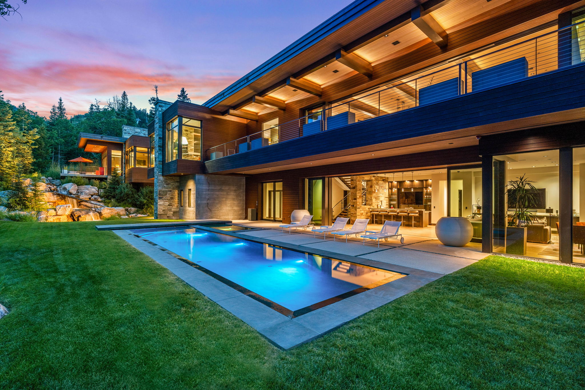 Modern architectural residence featuring a rectangular swimming pool, expansive patio, and manicured lawn