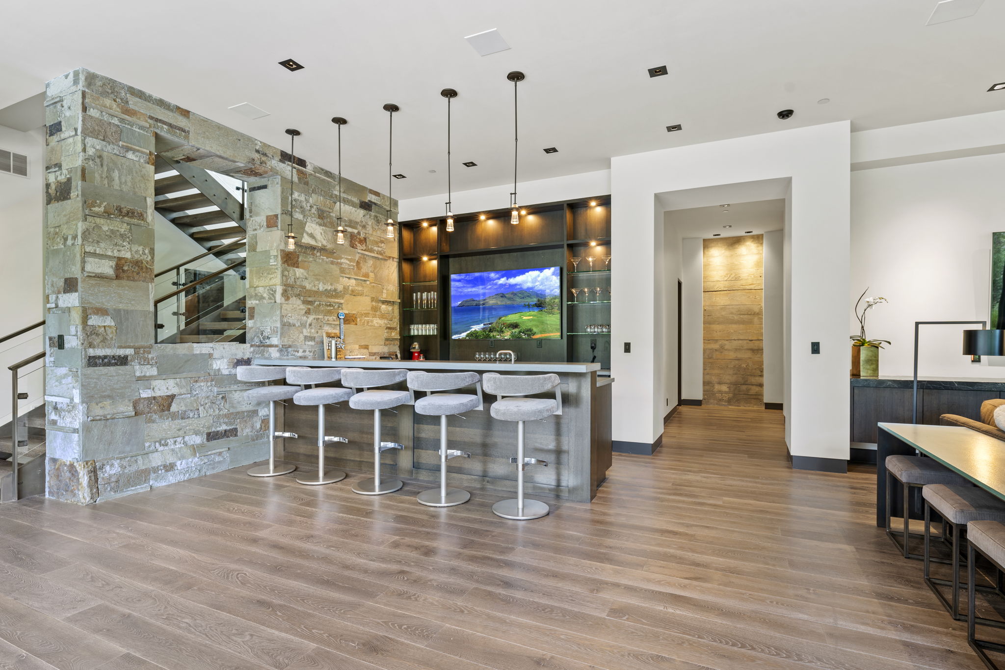 Built-in bar with pendant lighting, stone accents, and wood-finish flooring