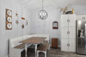 Dining area featuring a built-in bench seating, wood-finish flooring, and a contemporary spherical chandelier