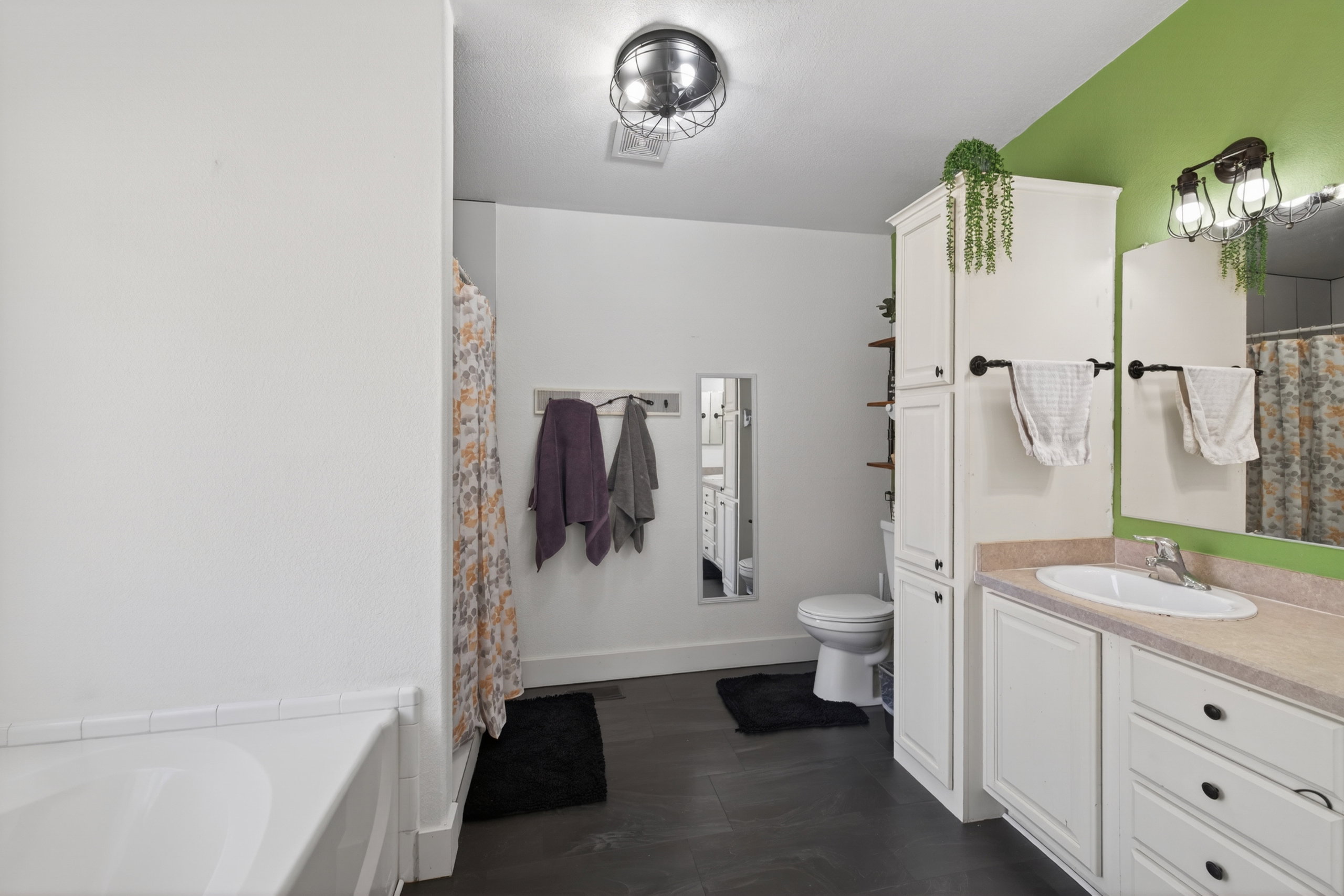 Bathroom featuring a single vanity with a white basin sink, light-colored countertop, and white cabinetry