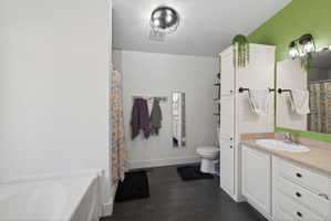 Bathroom featuring a single vanity with a white basin sink, light-colored countertop, and white cabinetry