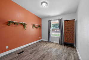 Room featuring wood-finish flooring, a neutral ceiling, and a window with exterior views