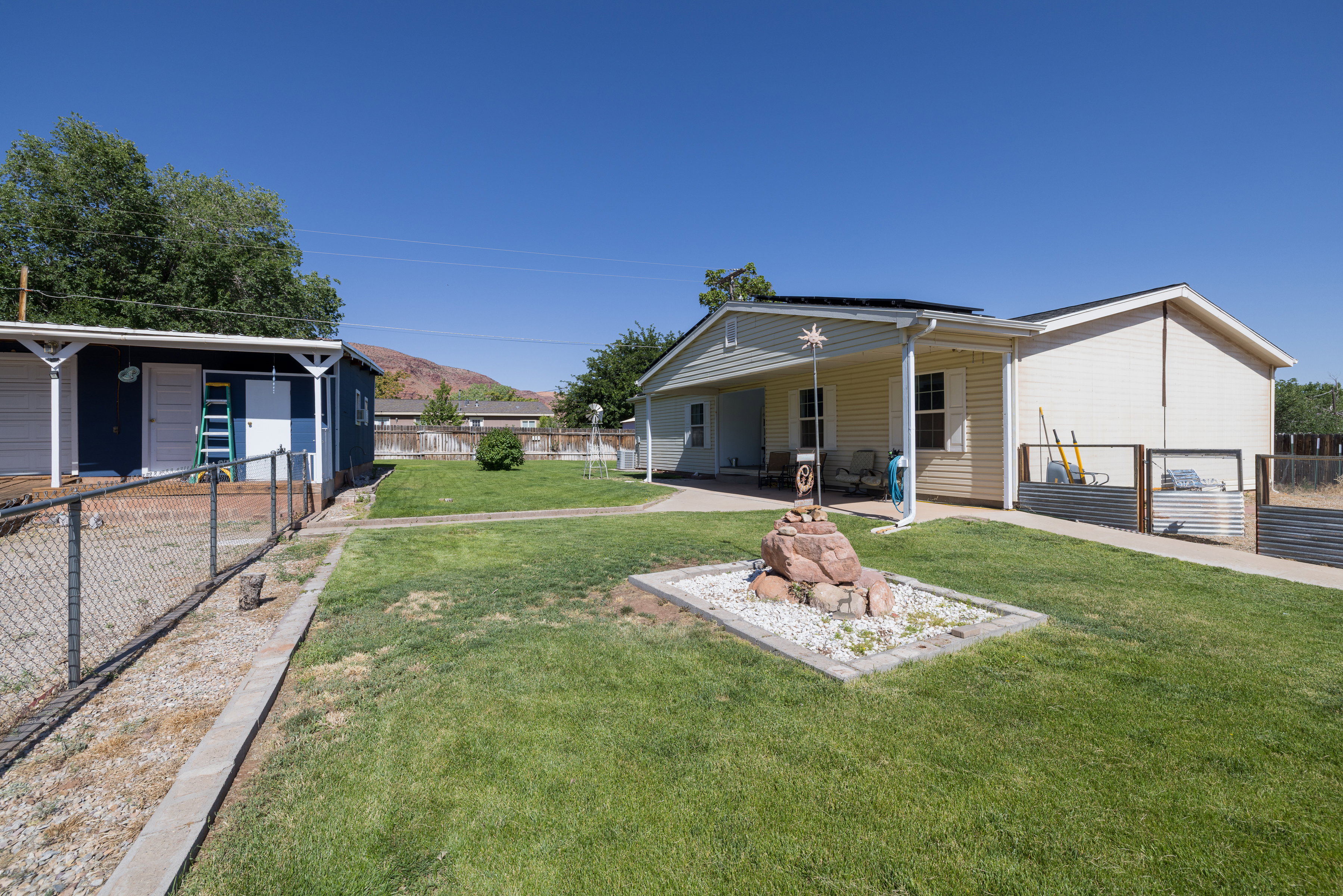 Expansive grassy yard area with a rock garden feature and concrete pathway