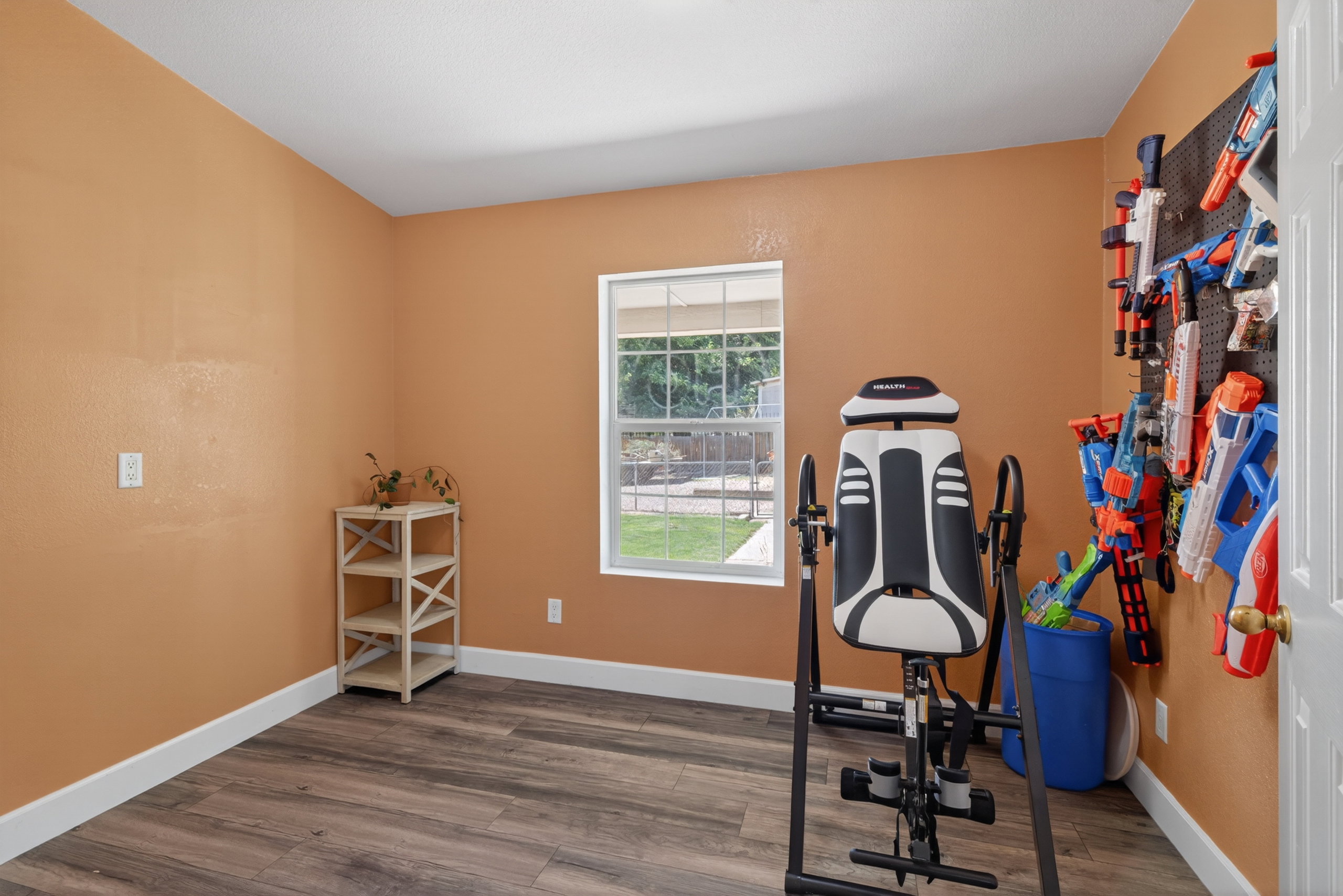 Room featuring wood-finish flooring, white baseboards, and a window with exterior views