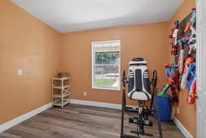 Room featuring wood-finish flooring, white baseboards, and a window with exterior views