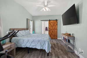 Vaulted ceiling bedroom featuring wood-finish flooring and a ceiling fan