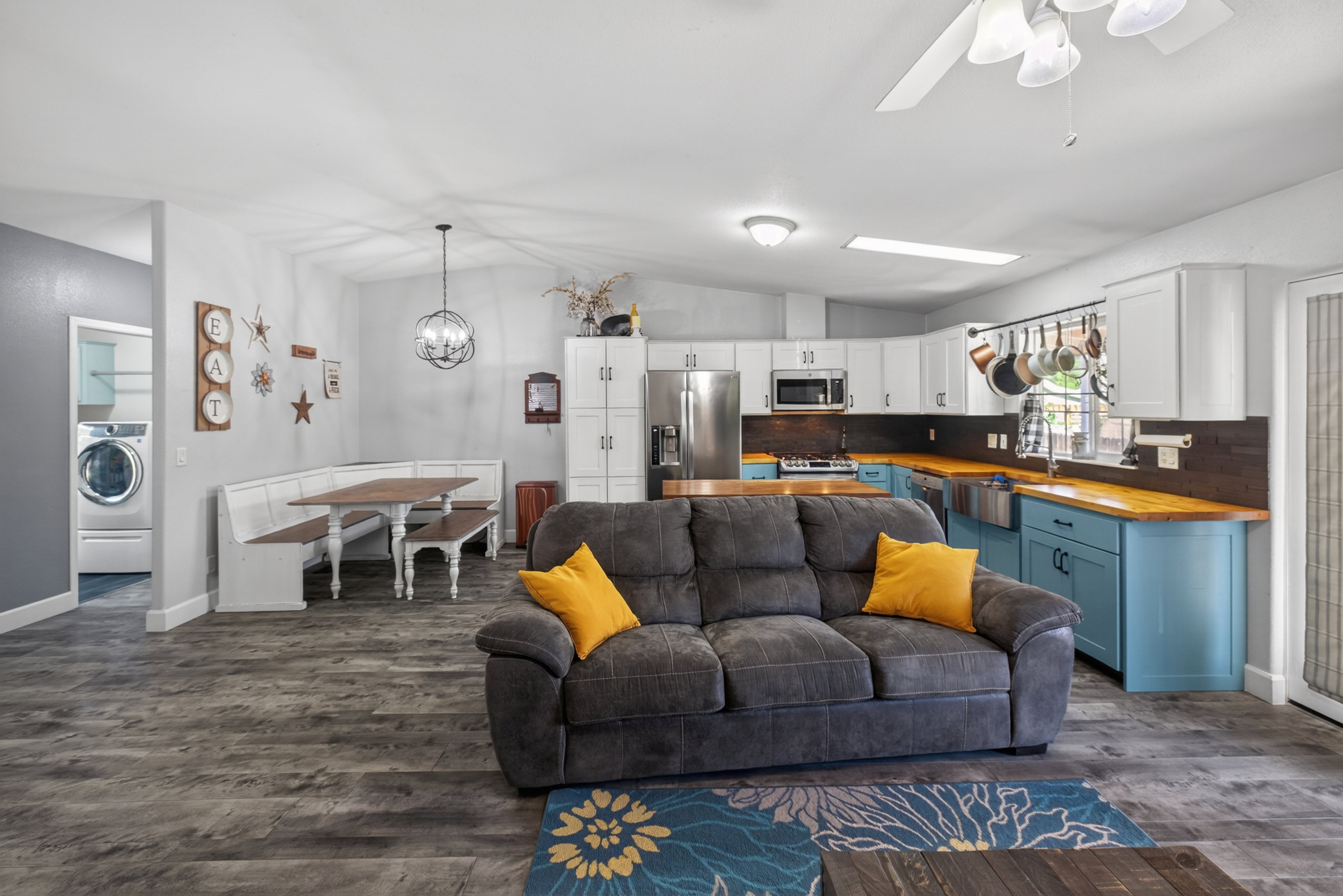 Open-concept interior featuring wood-finish flooring, a kitchen with light blue base cabinetry and wood countertops, and white upper cabinetry