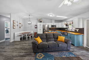 Open-concept interior featuring wood-finish flooring, a kitchen with light blue base cabinetry and wood countertops, and white upper cabinetry
