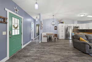 Open-concept living space with wood-finish flooring, vaulted ceilings, and a light blue wall finish