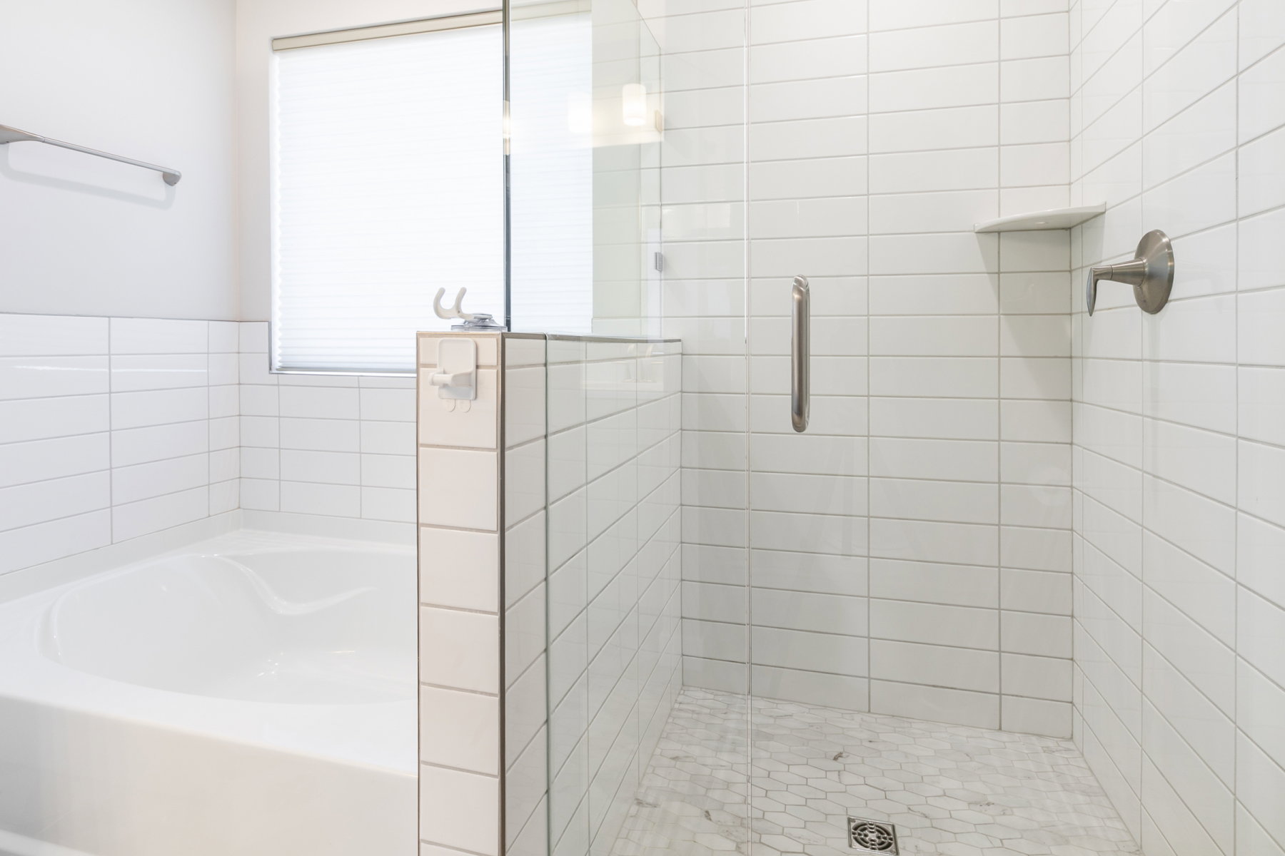 Contemporary bathroom featuring a built-in tub, a glass-enclosed shower with subway tile walls, a hexagonal tile shower floor, a recessed shower shelf, and brushed nickel fixtures