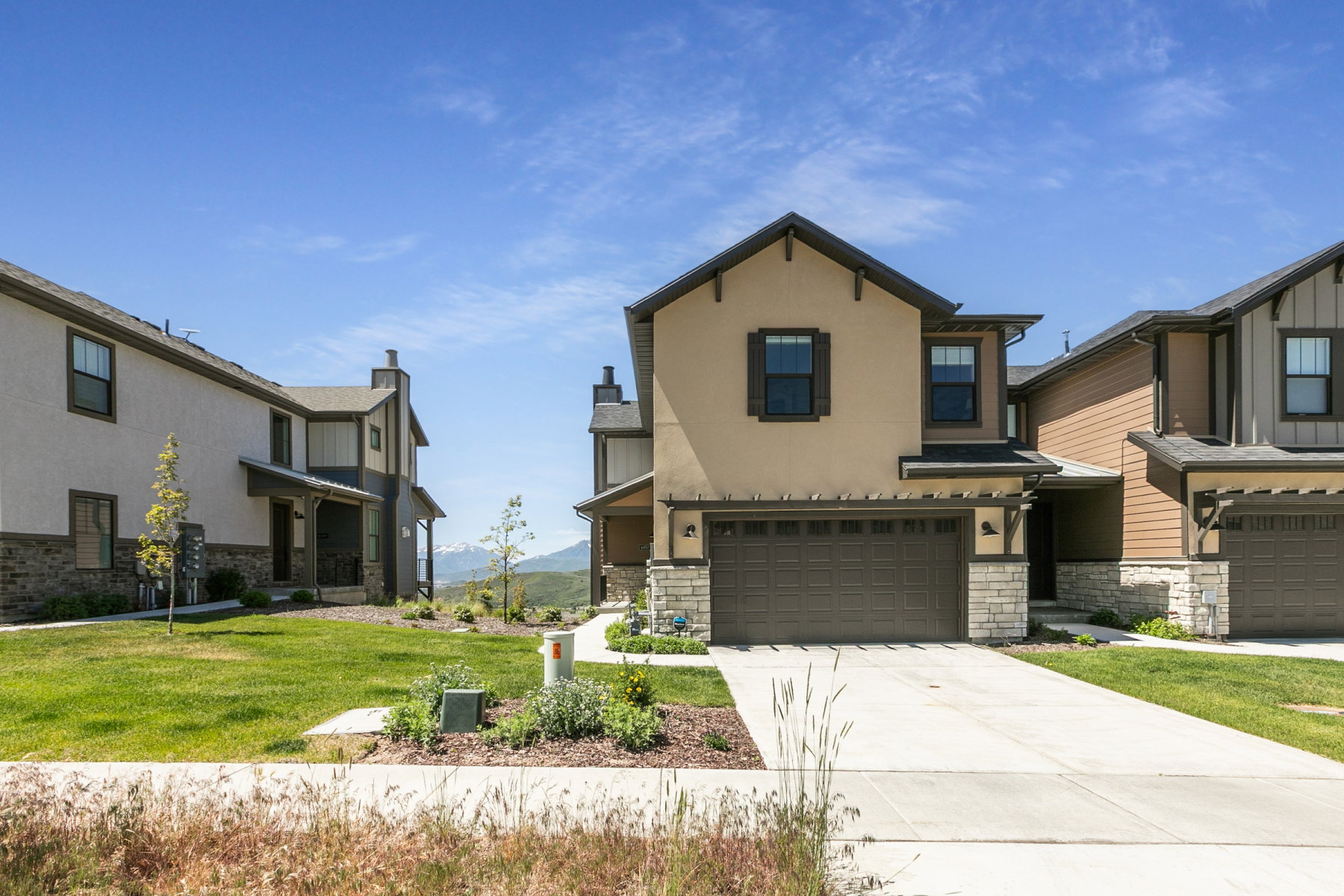 Contemporary stucco and stone-clad exterior with an attached two-car garage