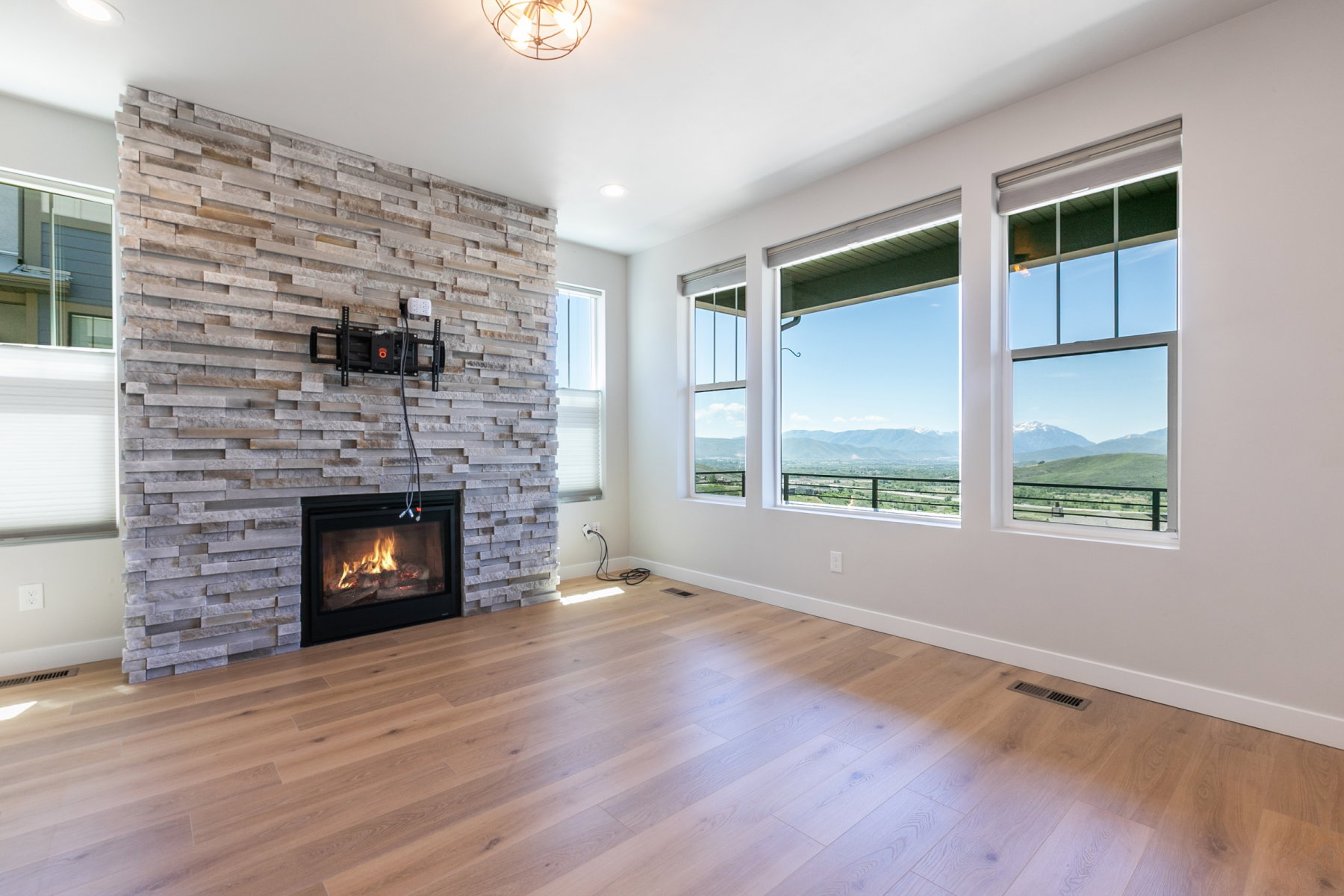 Light wood-finish flooring complements a stone-clad fireplace with an integrated firebox