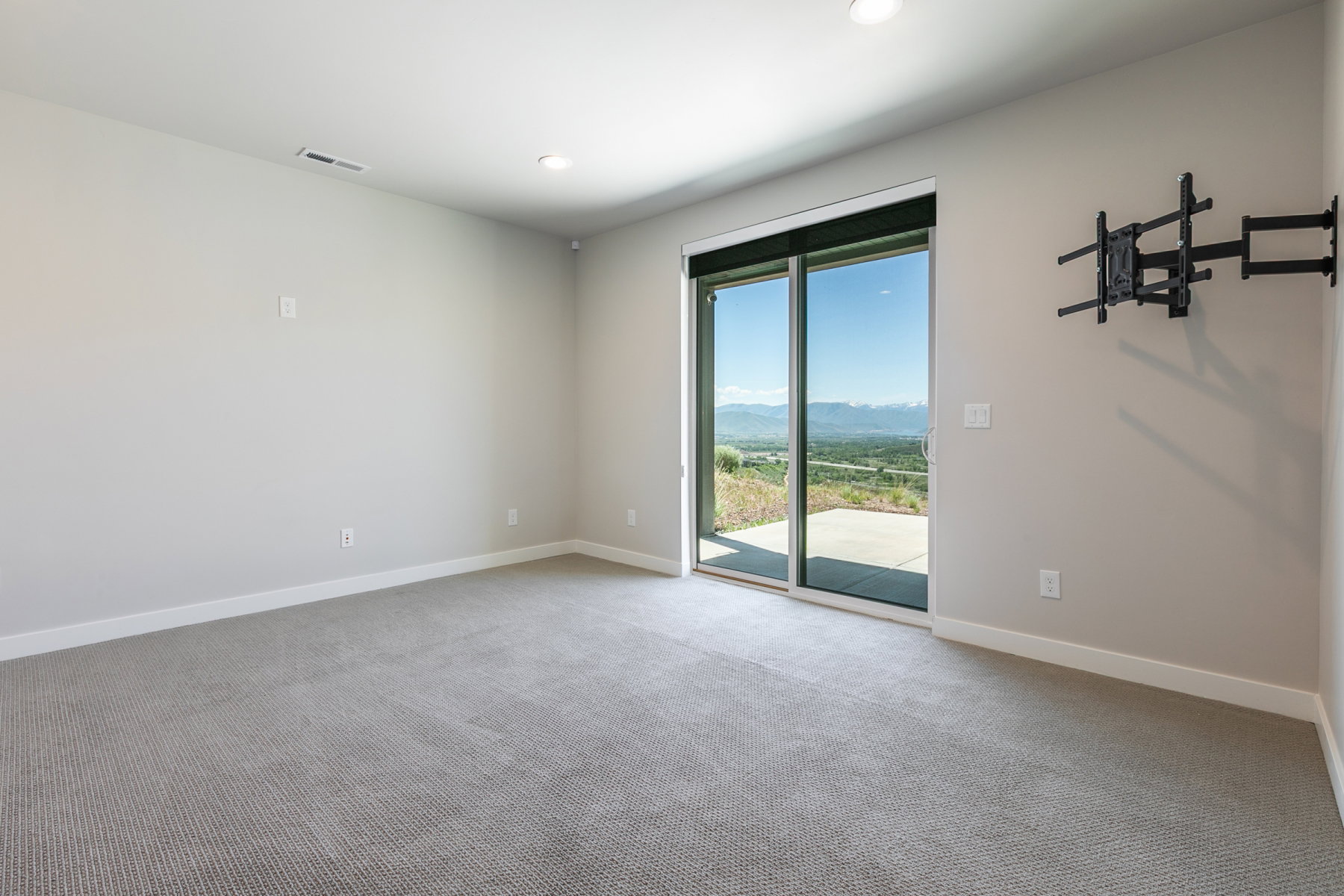 Sliding glass door opening to an outdoor patio with distant mountain scenery