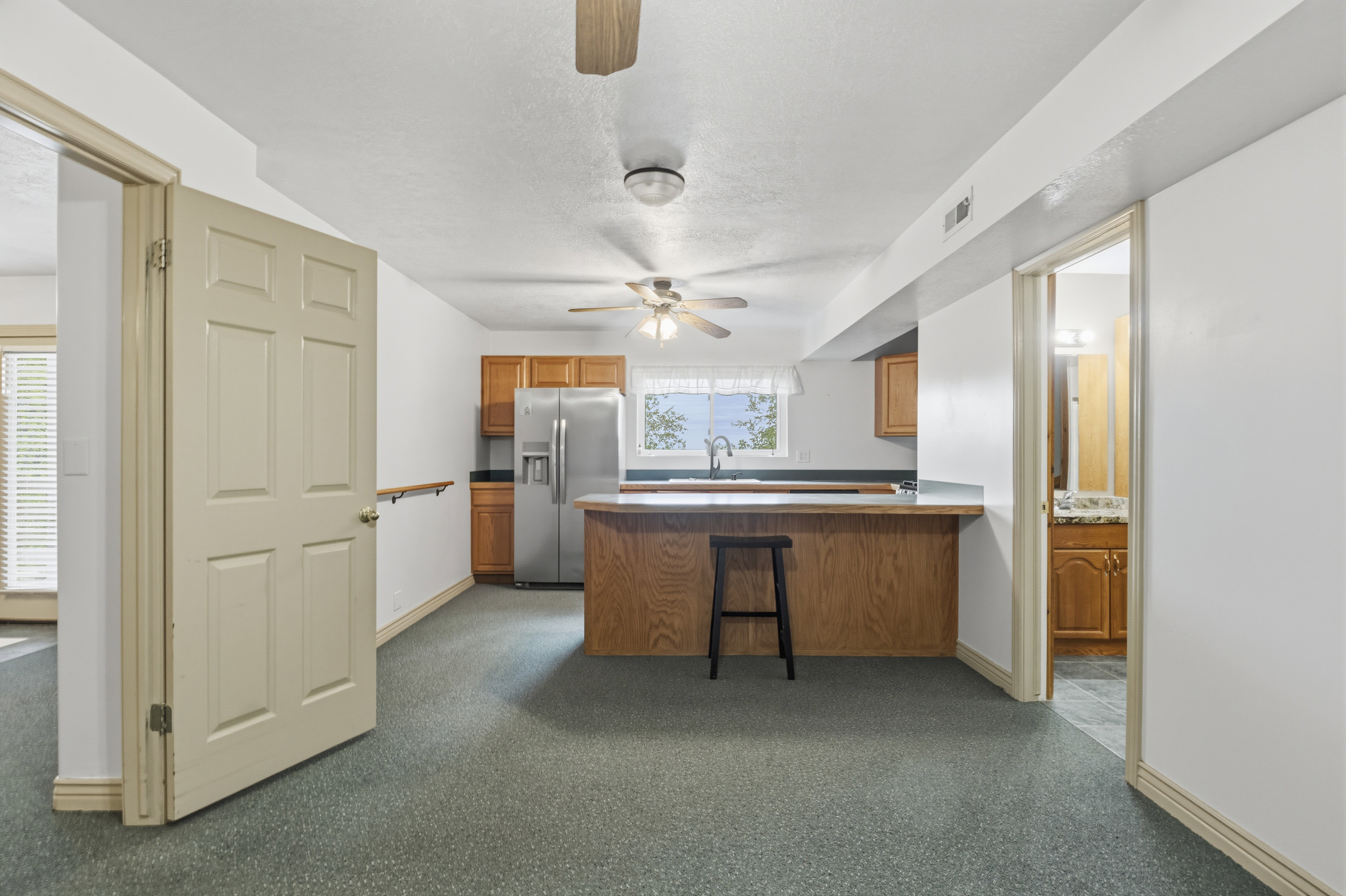 Kitchen area featuring wood-finish cabinetry, stainless steel refrigerator, and breakfast bar with countertop