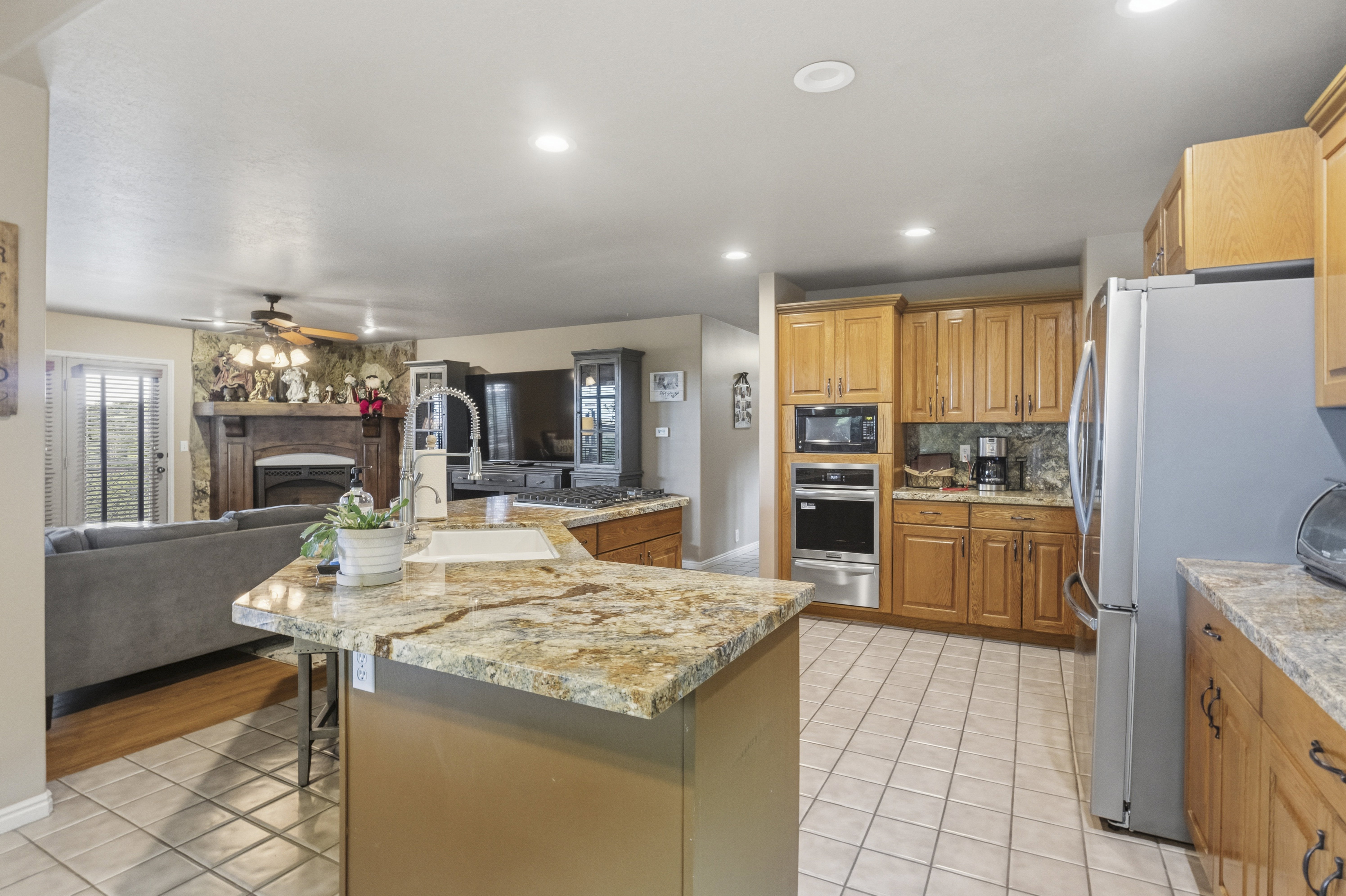 Kitchen featuring a large island with a surface, wood cabinetry, tile flooring, and stainless steel appliances including a built-in microwave and oven