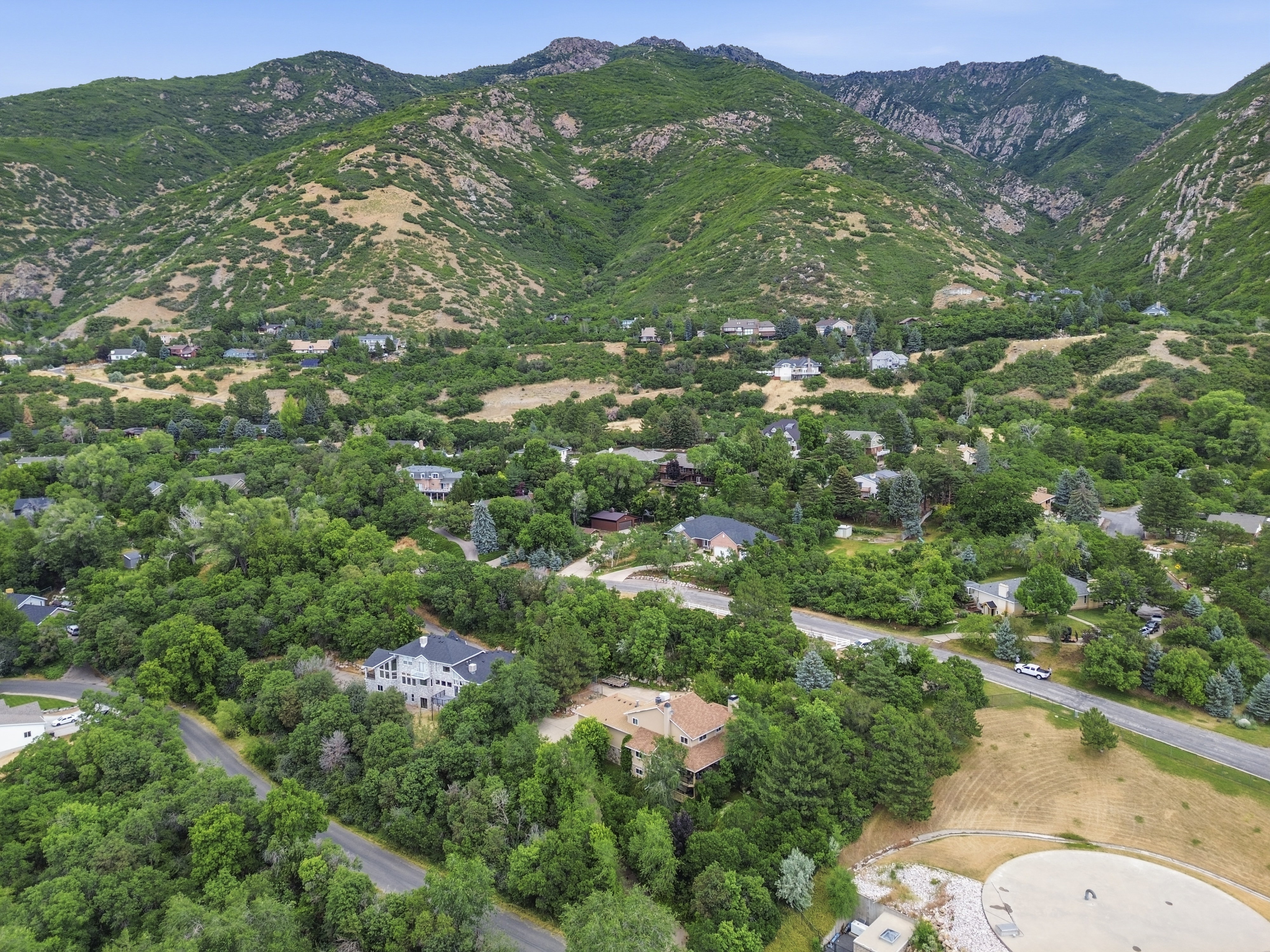 Aerial perspective showcasing a residential area nestled at the base of lush, green mountains