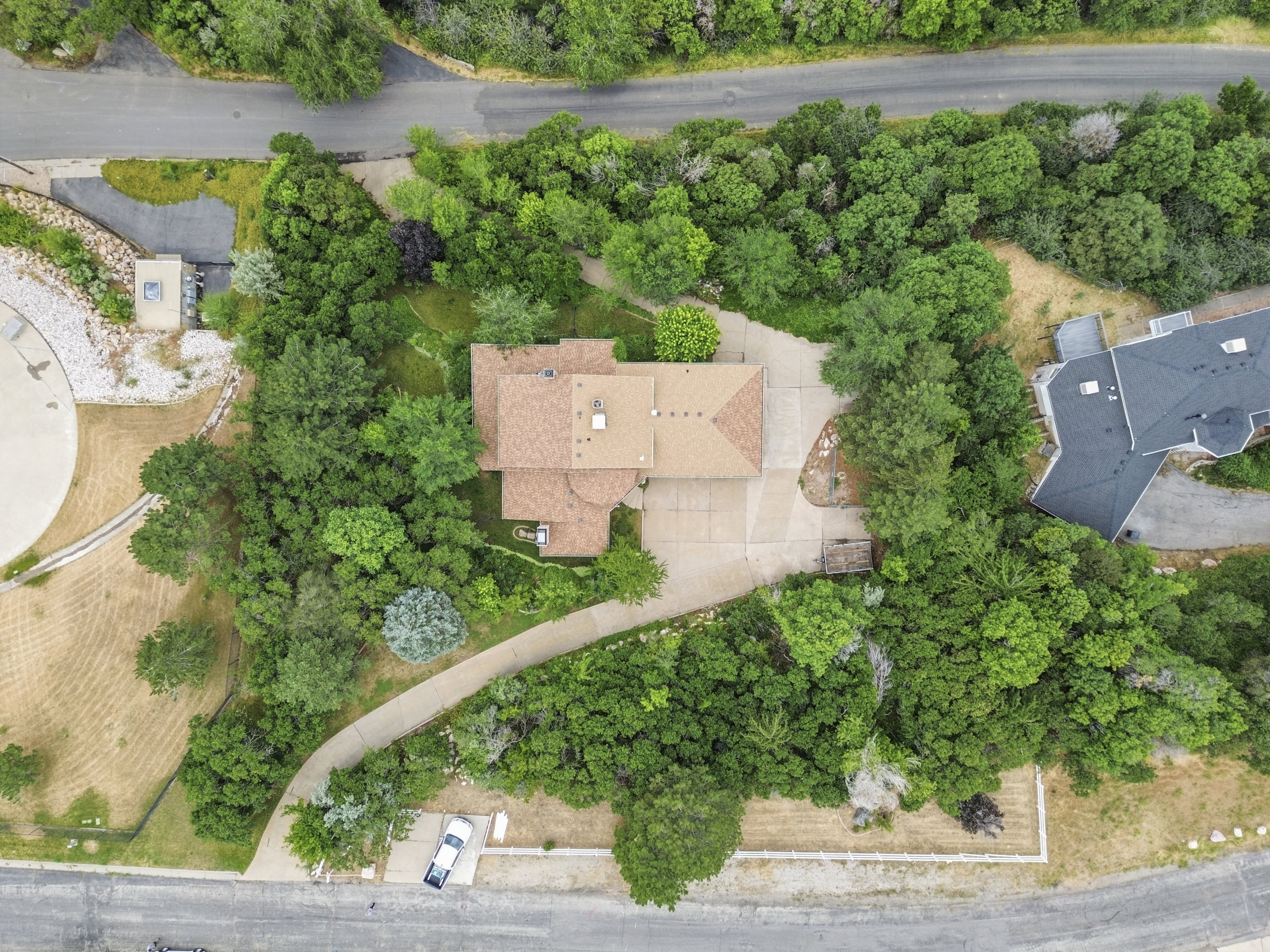 Property featuring a private driveway, mature trees, and a tan shingle roof