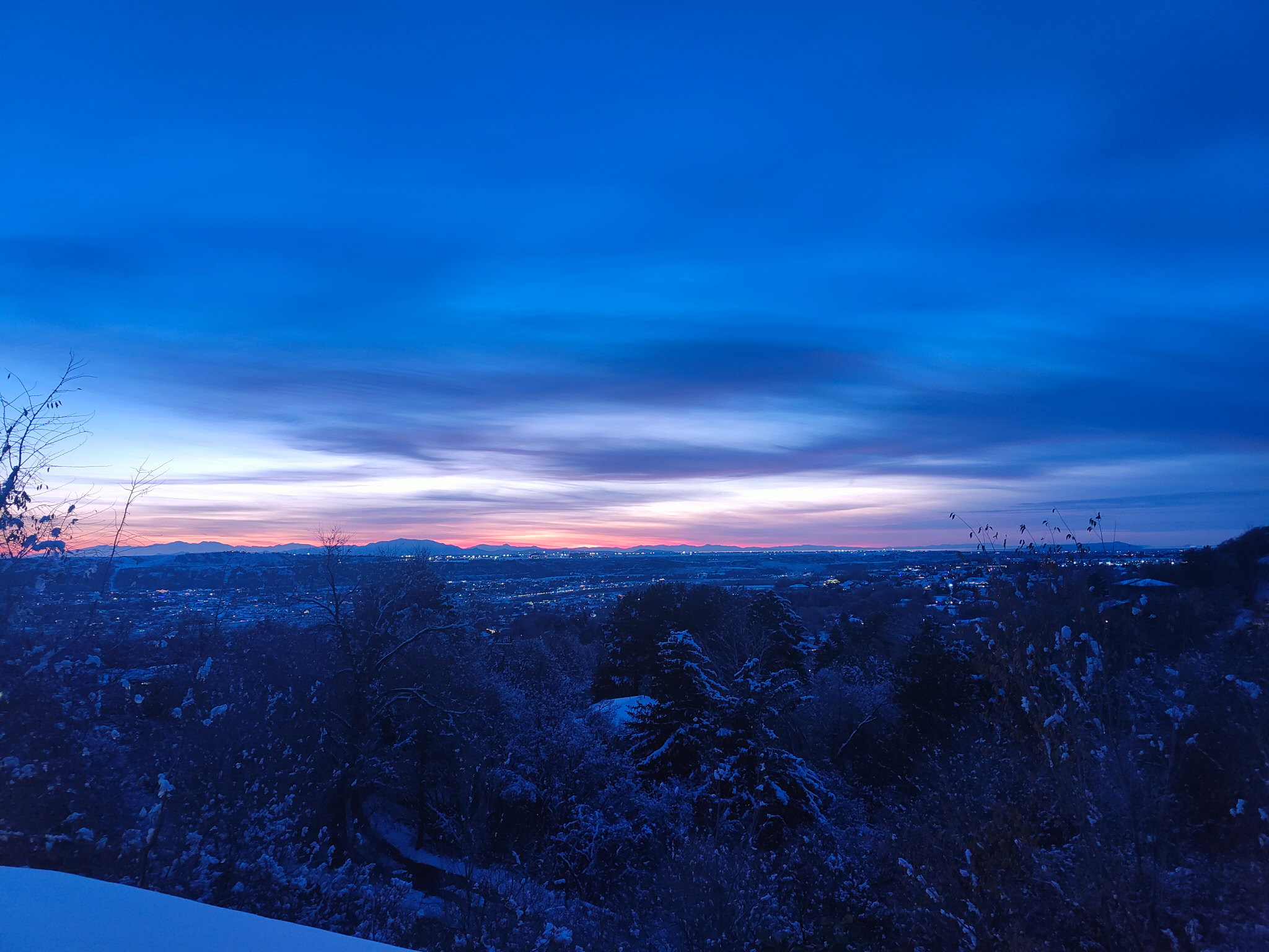 Expansive mountain range backdrop and city lights visible on the horizon