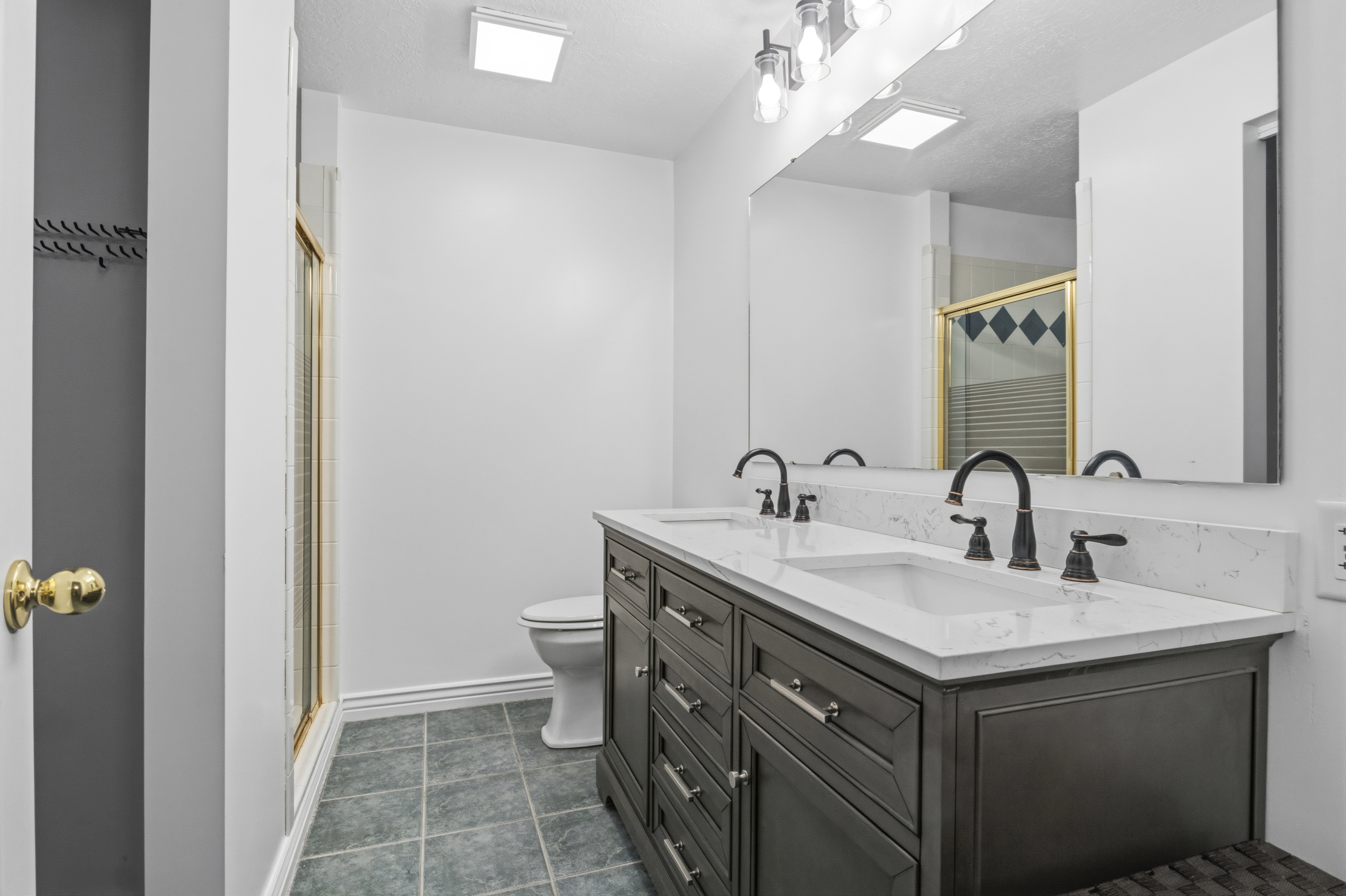 Double vanity with dark wood-finish cabinetry, white countertops, and dual undermount sinks with matte black fixtures