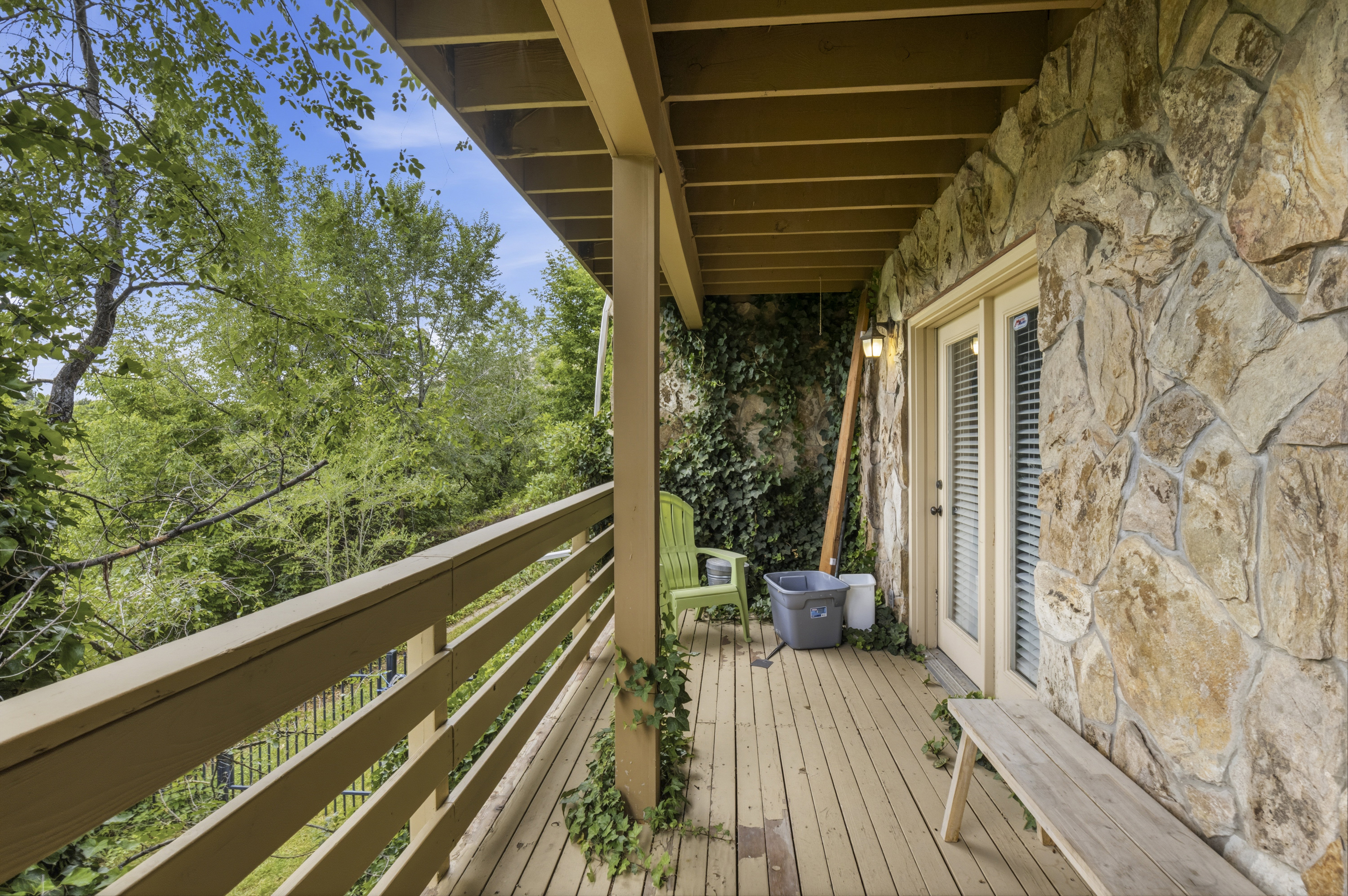 Expansive wood-finish deck with a wood railing and natural stone exterior