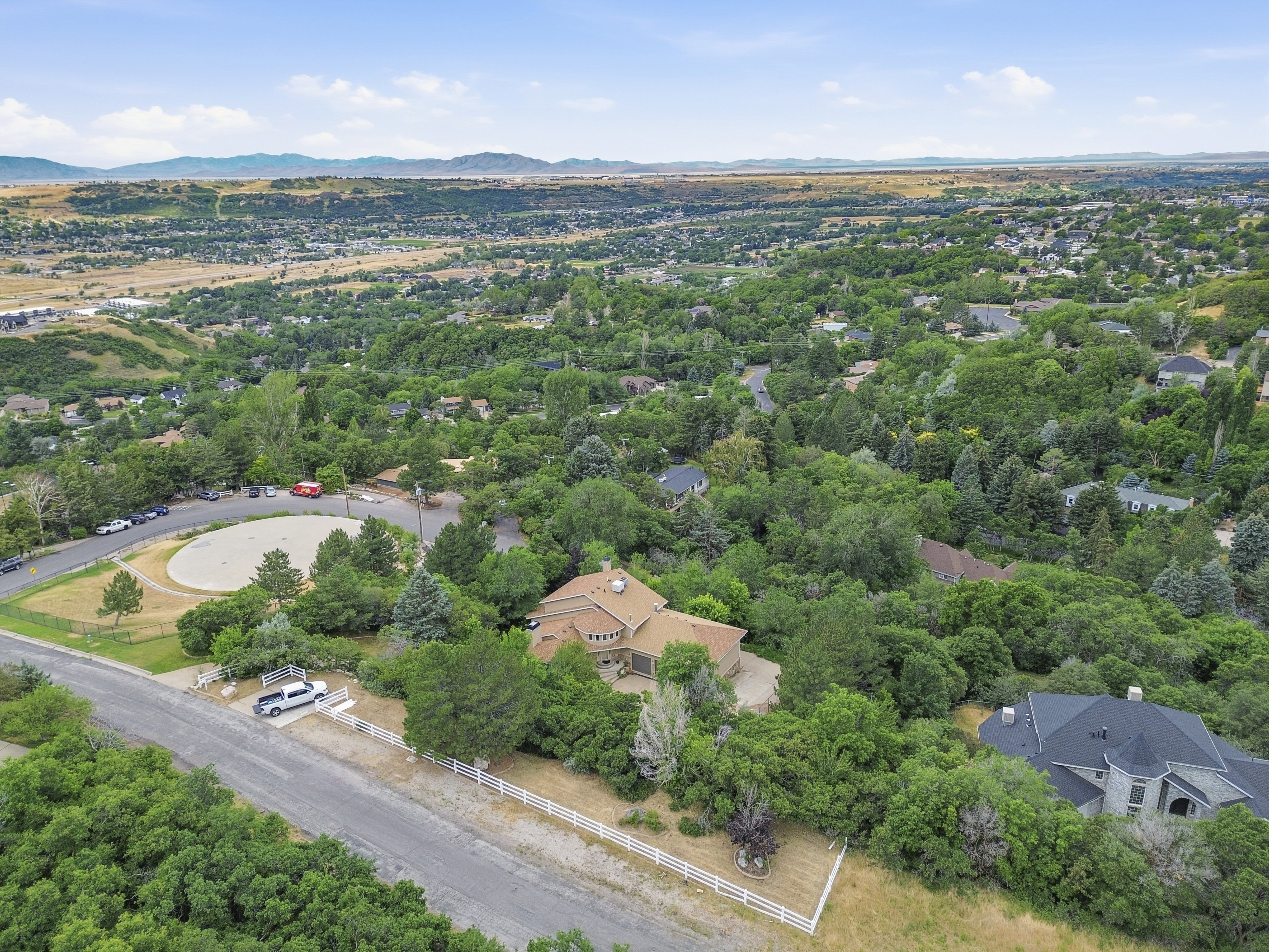 Expansive hillside property featuring a multi-level residence with a distinct curved facade, surrounded by mature trees