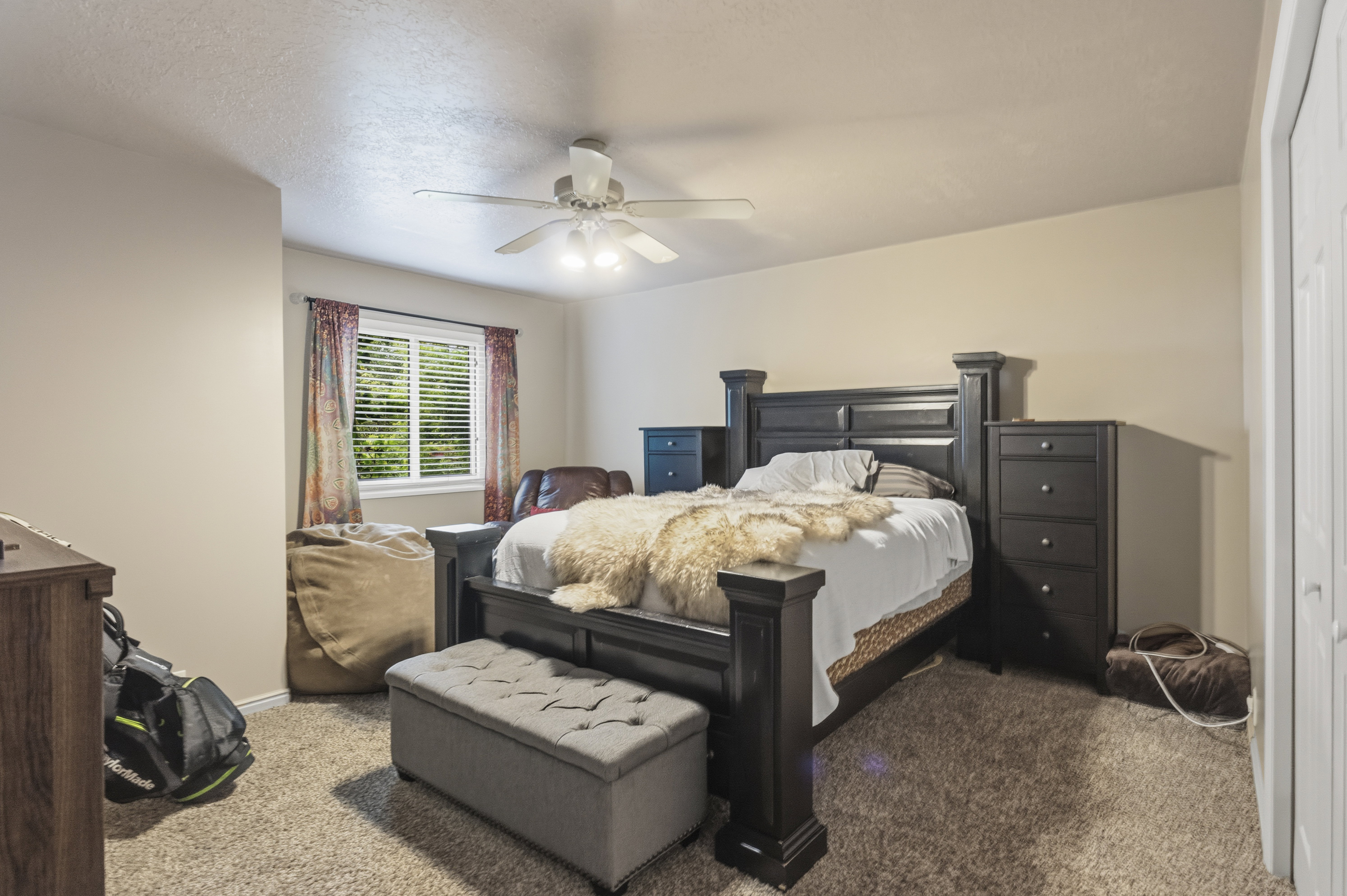 Carpeted room with neutral wall tones and a ceiling fan with integrated lighting
