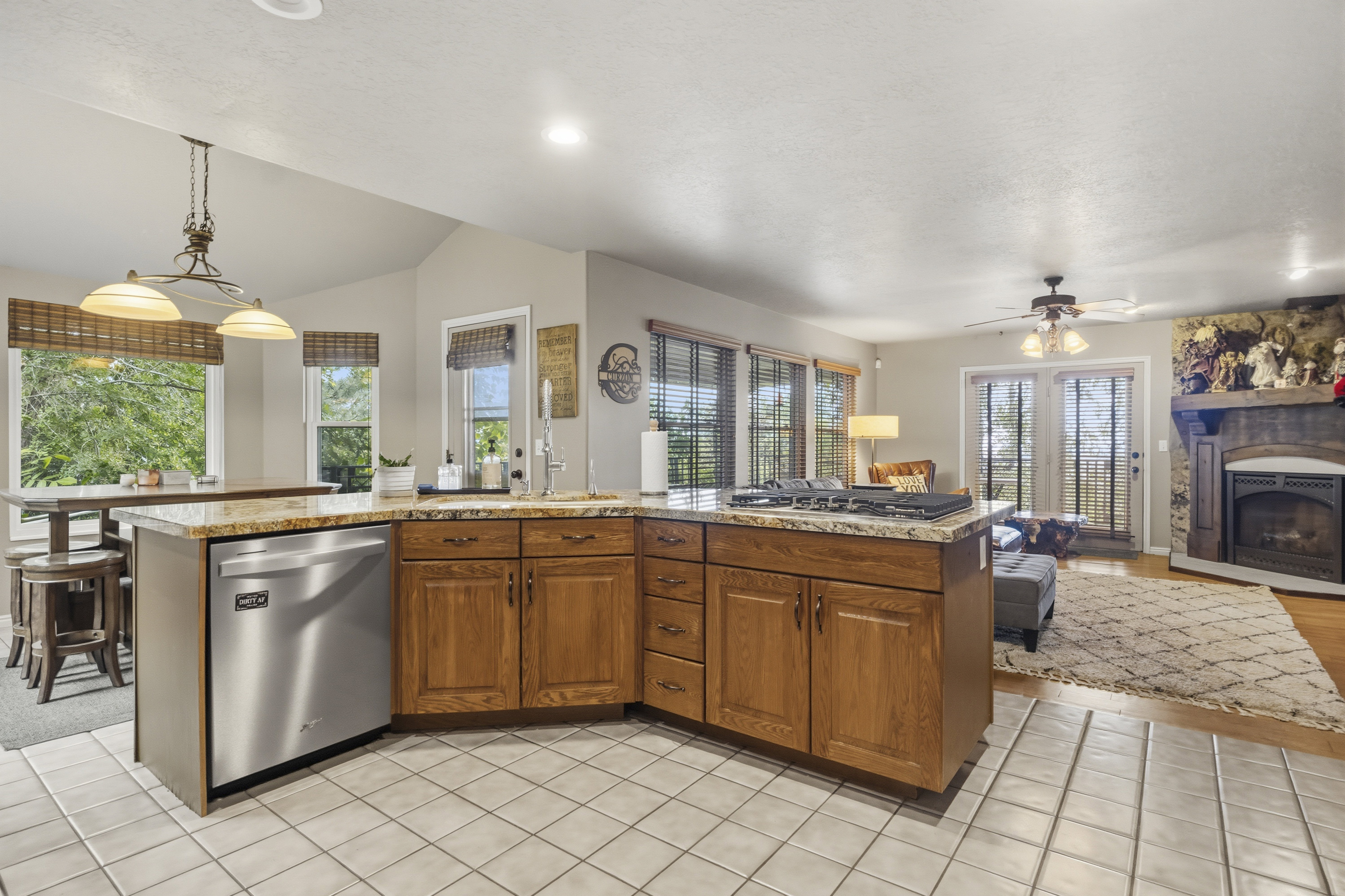 Open-concept kitchen featuring wood cabinetry, granite countertops, an integrated gas cooktop, and a stainless steel dishwasher